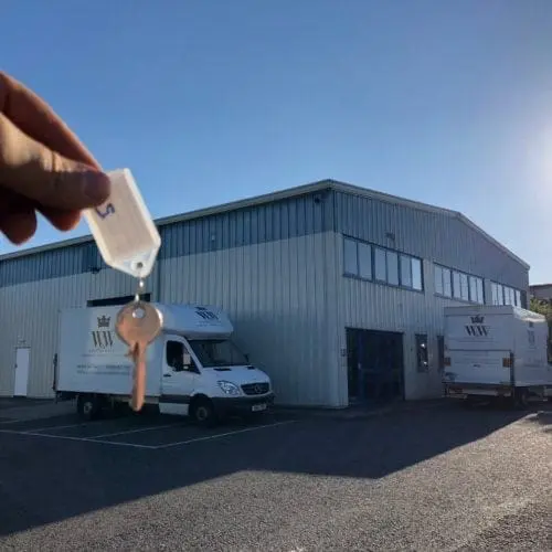 A key is dangled in front of the new William's and White depot in Chippenham with two vans parked outside.